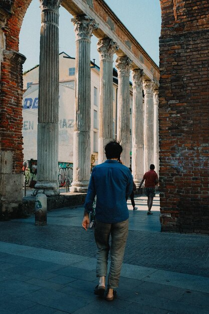 Foto un hombre con una camisa azul en una llamada telefónica mientras camina en la colonne di san lorenzo en milán stock