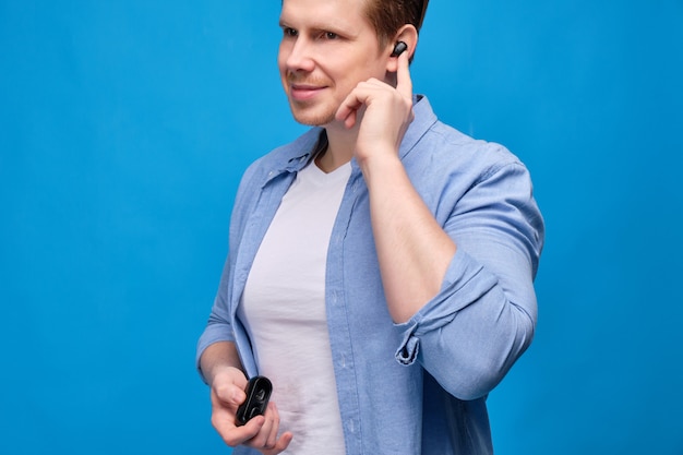 Un hombre con una camisa azul se puso un auricular inalámbrico y enciende la música.