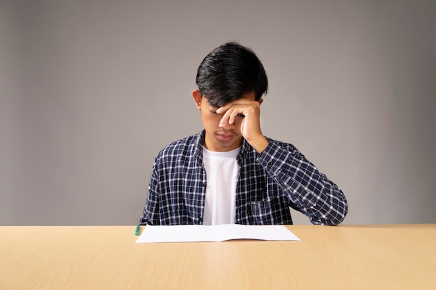 Hombre con camisa azul sentado estresado mirando sus documentos de trabajo