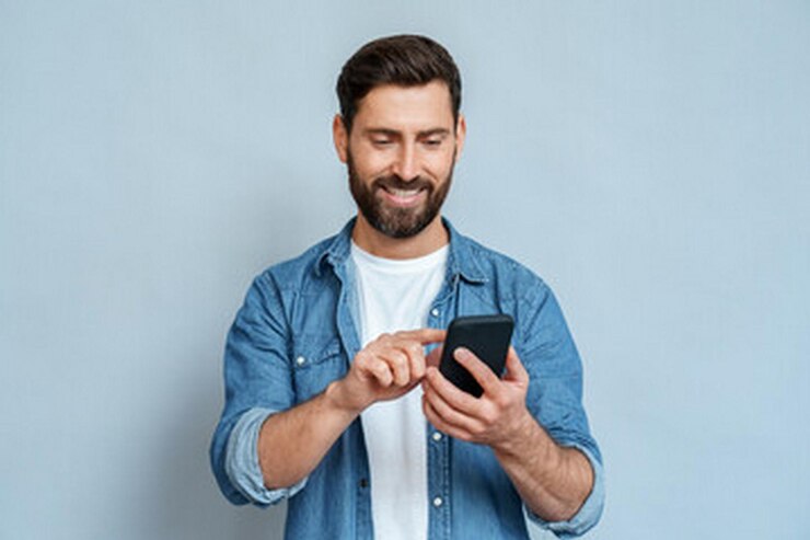 un hombre con una camisa azul sostiene un teléfono