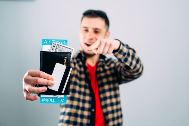 Foto hombre en camisa con billetes de avión, tarjeta de crédito y pasaporte en mano