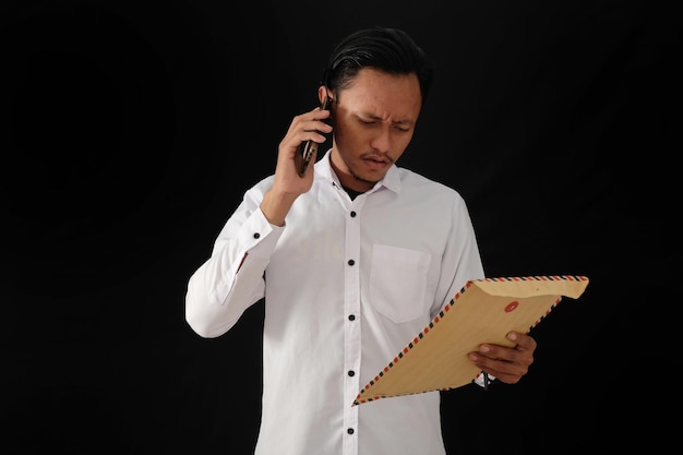 Un hombre con una camisa blanca está hablando por teléfono y sostiene una carpeta con la palabra teléfono.