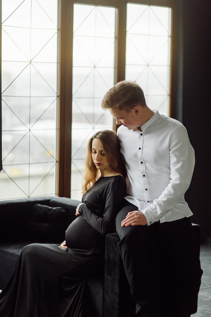 Hombre con camisa blanca y mujer con vestido negro Foto de embarazo