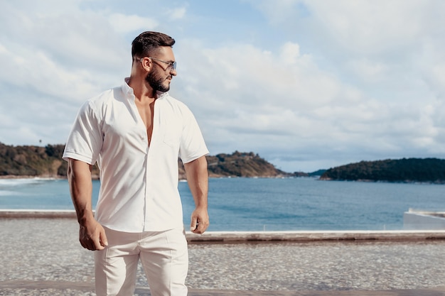 con camisa blanca pantalones de pie en una playa | Foto