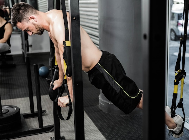 Hombre sin camisa colgando en el teleférico del gimnasio crossfit