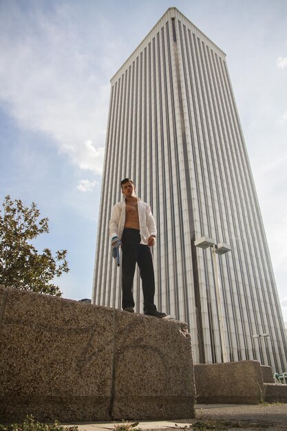 Foto hombre con camisa completamente desabrochada de pie contra un edificio moderno en la ciudad