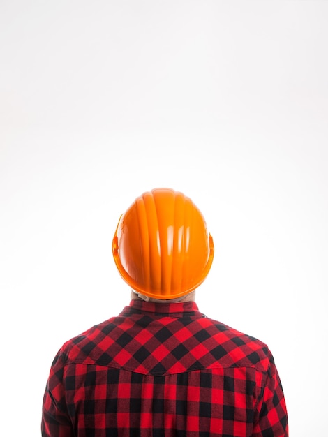 Un hombre con una camisa a cuadros y un casco de construcción desde la vista posterior desde atrás aislado