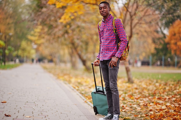 Hombre en camisa a cuadros, con maleta y mochila