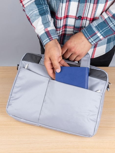 Foto un hombre con una camisa a cuadros saca un cuaderno azul de una elegante bolsa para el trabajo