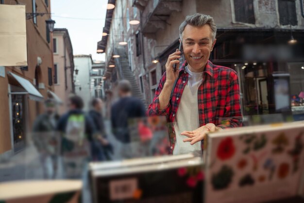 Foto hombre con camisa a cuadros con un teléfono cerca del escaparate