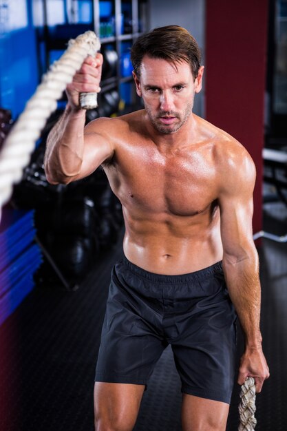 Hombre sin camisa con cuerda en el gimnasio