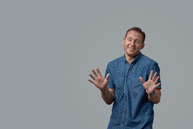 Un hombre en una camisa con una expresión de disculpa sobre un fondo gris Banner conceptual para el espacio de copia publicitaria diseño comercial de fondo gris