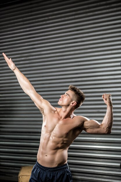 Hombre sin camisa flexionando los músculos en el gimnasio.