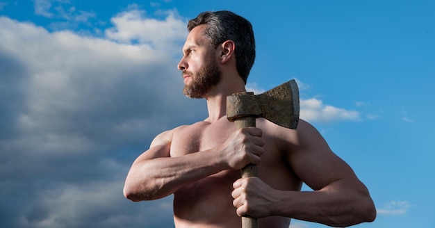 Hombre sin camisa con hacha hombre caucásico mantenga hacha brutal hombre sobre fondo de cielo