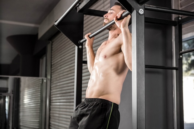 Hombre sin camisa haciendo levantarse en el gimnasio de crossfit