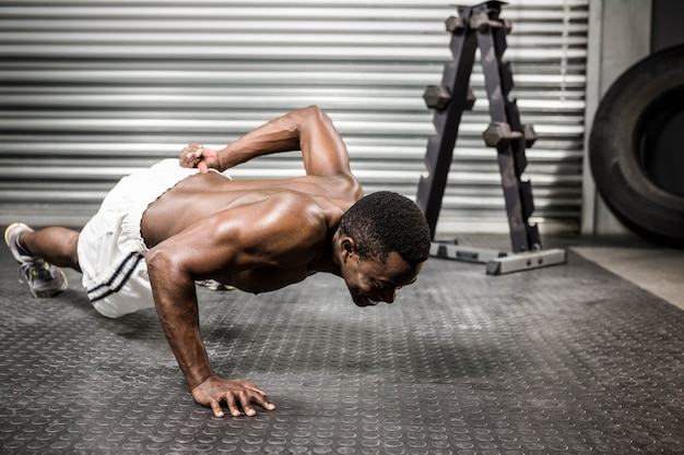 Hombre sin camisa haciendo push up en el gimnasio de crossfit