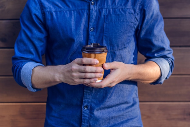 Hombre en camisa de jeans sosteniendo una taza de café