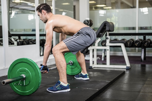 Hombre sin camisa levantando pesas en el gimnasio