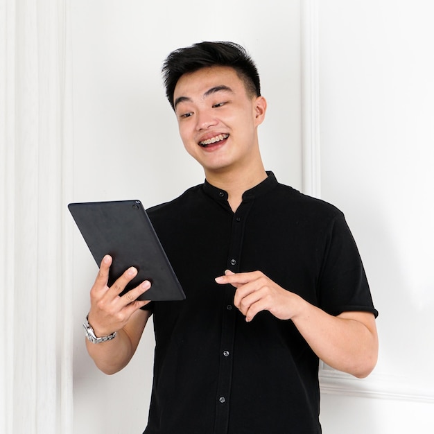 Un hombre con una camisa negra sostiene una tableta y sonríe.