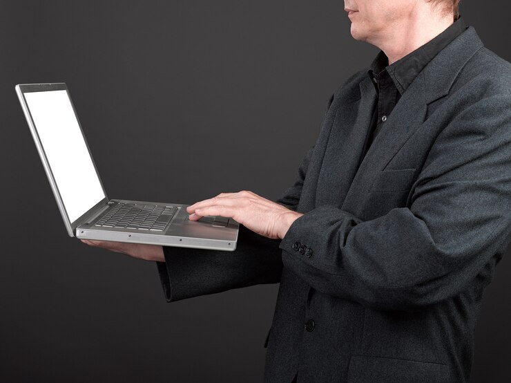 Foto hombre de camisa negra y traje sosteniendo una laptop