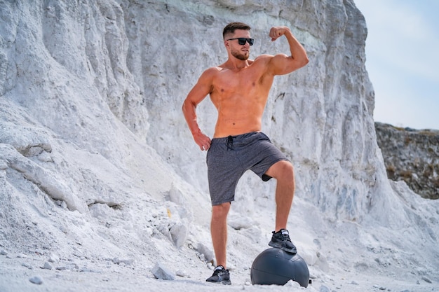 Un hombre sin camisa parado frente a una montaña.