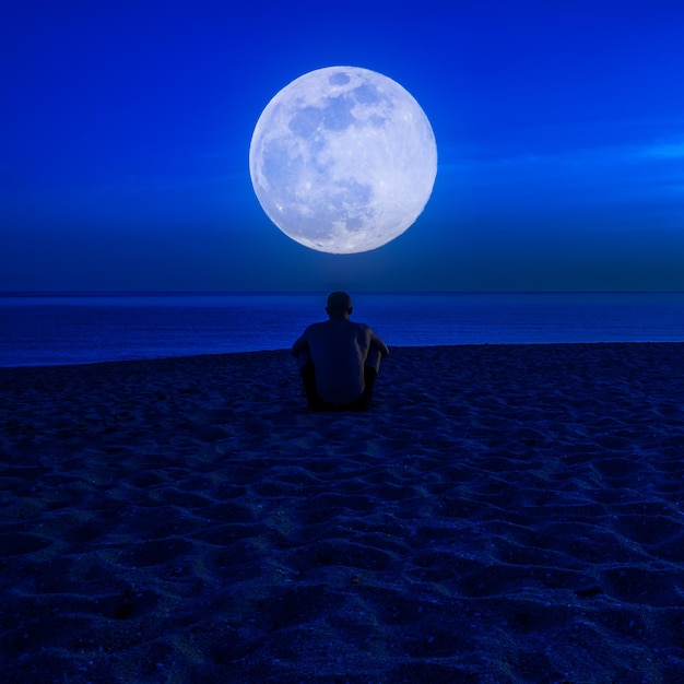 Hombre sin camisa en la playa por la noche