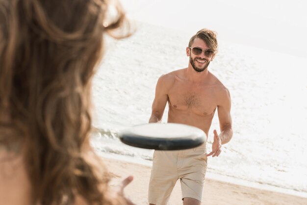 Hombre sin camisa que disfruta jugando y divirtiéndose en la playa en verano