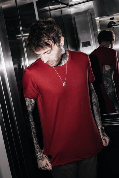 Foto un hombre con una camisa roja se para en un ascensor y mira a la cámara.