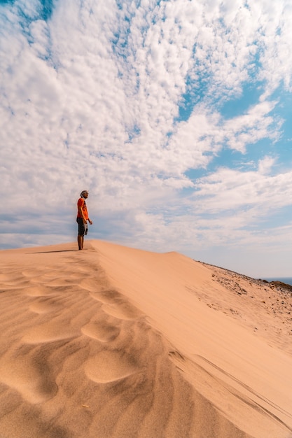 Un hombre con una camisa roja y un turbante en la cabeza, caminando en el desierto de la duna.