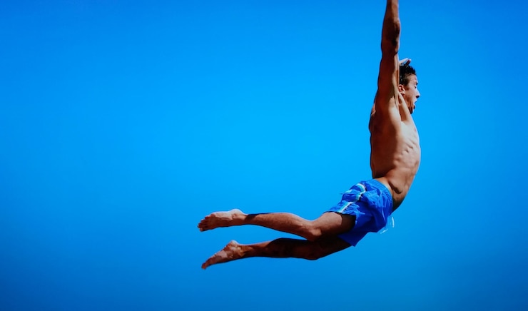 Foto hombre sin camisa saltando contra el cielo azul claro