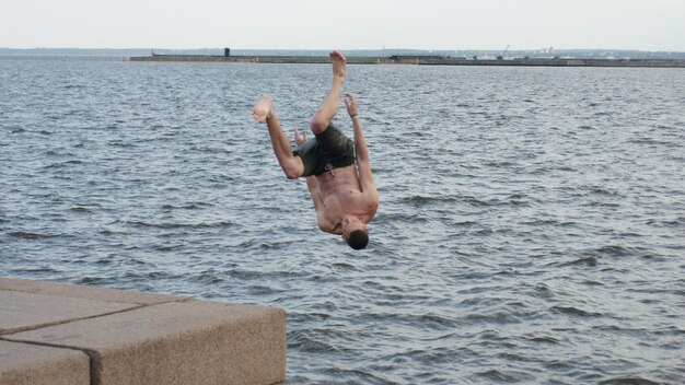 Foto hombre sin camisa saltando en el mar