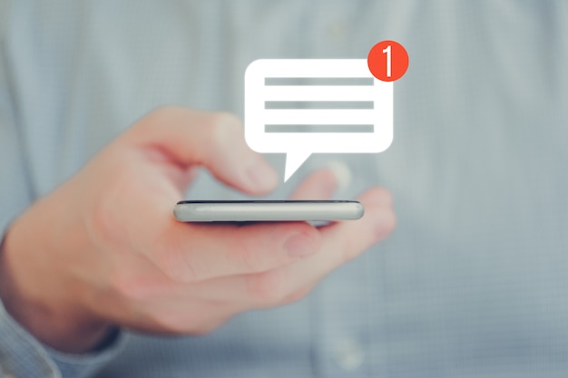 Foto un hombre en una camisa sostiene un teléfono con la mano. icono de mensaje de notificación abstracta. concepto de redes sociales.