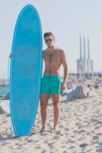 Hombre sin camisa con tabla de surf en la playa