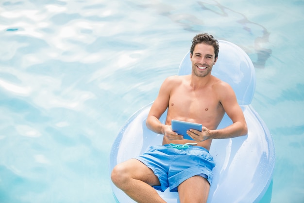 Hombre sin camisa con tableta digital en anillo inflable