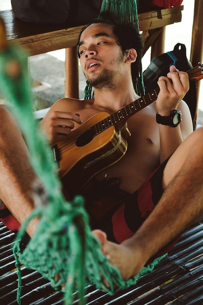 Foto hombre sin camisa tocando la guitarra