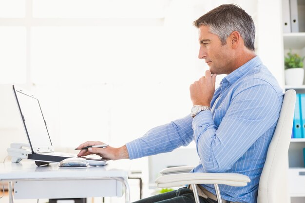 Hombre en camisa usando laptop y pensando