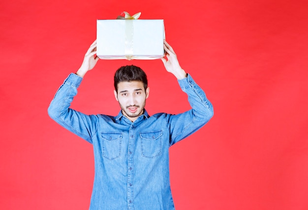 Hombre en camisa vaquera con caja de regalo plateada.