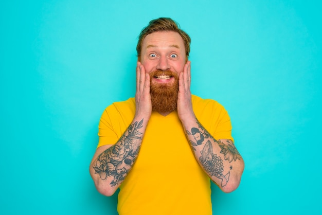 Hombre con camiseta amarilla y barba está muy feliz