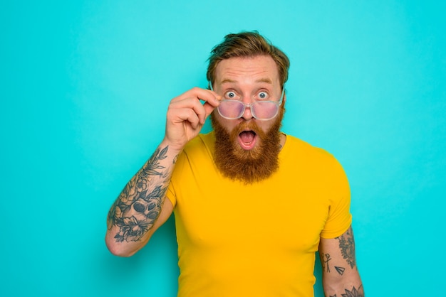 Hombre con camiseta amarilla y barba está sorprendido por algo