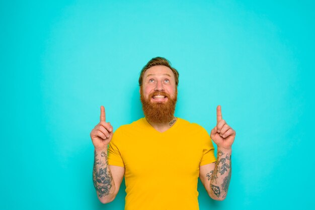 Hombre con camiseta amarilla y barba está sorprendido por algo