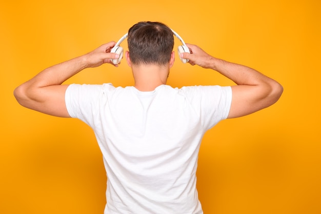 Foto un hombre con una camiseta blanca con auriculares blancos en la cabeza está de espaldas.