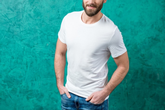 Foto hombre de la camiseta blanca con espacio para copiar y pegar de pie sobre el fondo de la pared verde.