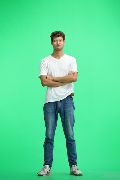 Foto un hombre con una camiseta blanca sobre un fondo verde a plena altura cruzó los brazos