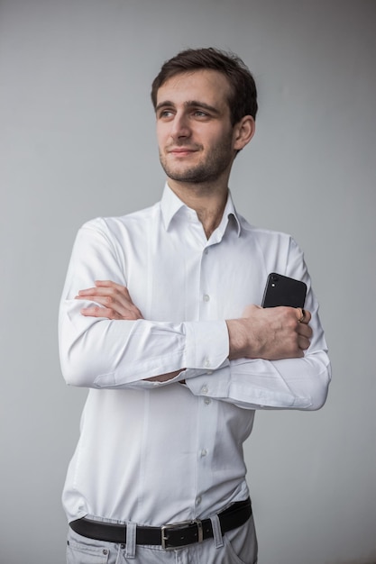 Un hombre con una camiseta blanca sosteniendo un teléfono