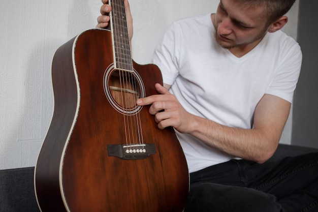 Un hombre con una camiseta blanca tocando una guitarra.