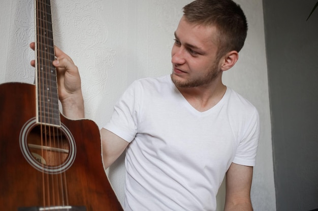 Un hombre con una camiseta blanca tocando una guitarra.