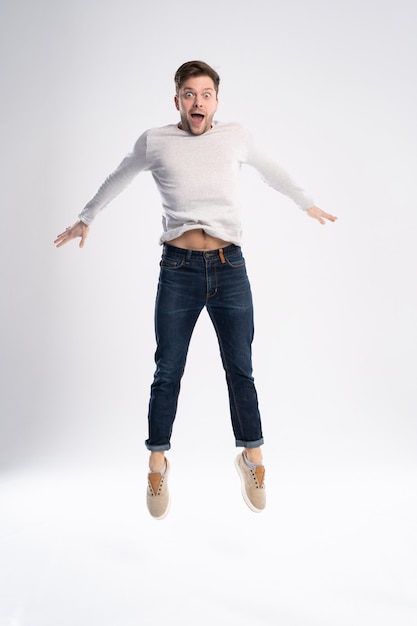 Hombre en camiseta casual y jeans saltando aislado sobre fondo blanco.