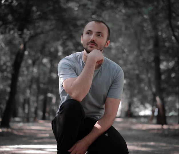 Un hombre con una camiseta gris se sienta y piensa