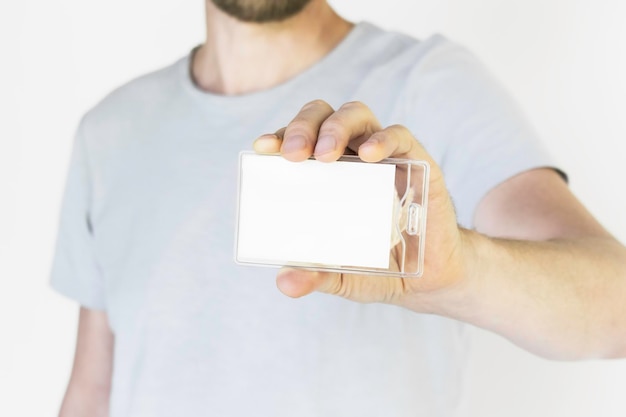 un hombre con una camiseta gris sosteniendo y mostrando una tarjeta de identificación vacía en una caja de plástico