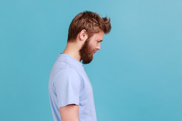 Hombre en camiseta mirando a la cámara con cara de tristeza insatisfecha expresando dolor de mal humor